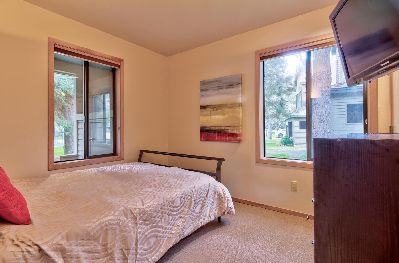 A bedroom with a bed, a window, and a television.