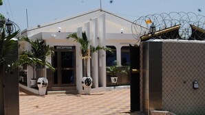 A reception area with a sign, potted plants, and a tiled entrance. - Madison Executive Guesthouse (Accra)