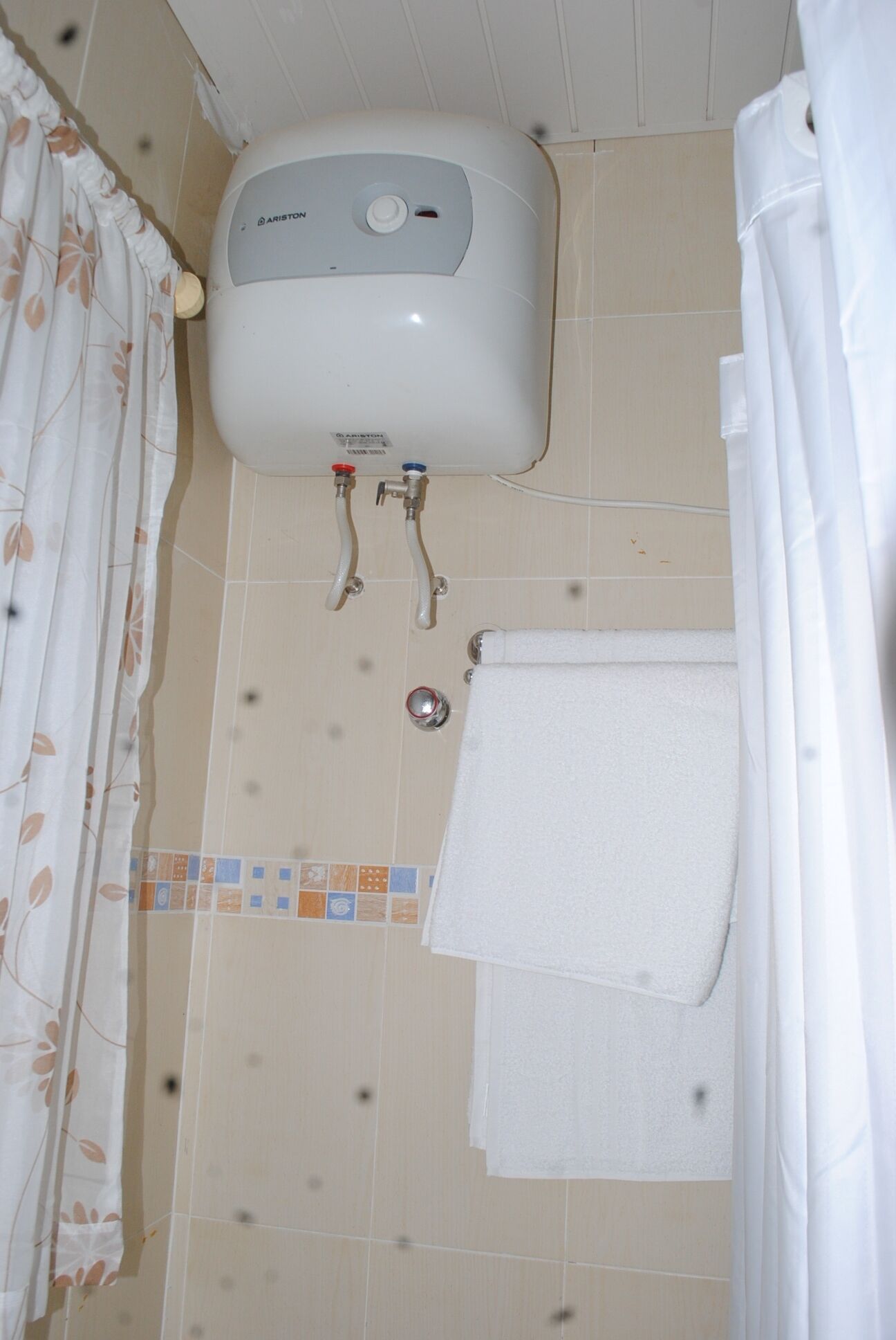 Un bany amb un vàter blanc, un penjador de tovalloles i un cortineta de bany.