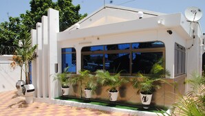 A modern building with large windows, a checkered tile entrance, and potted plants. - Madison Executive Guesthouse (Accra)