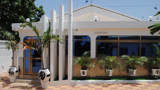 A modern building with a reception area, potted plants, and a checkered floor. - Madison Executive Guesthouse (Accra)