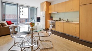 Una cocina moderna con armarios de madera, una mesa de comedor de vidrio y un sofá con un cojín rojo.