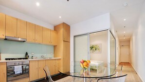 Una cocina moderna con armarios de madera, una mesa de comedor de vidrio y un frutero.