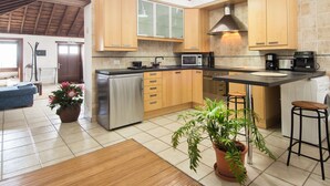 Eine moderne Küche mit Holzausstattung, einem Edelstahlkühlschrank, einer Mikrowelle und einer Kaffeemaschine.