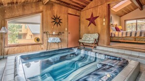 Ett spa-rum med ett bubbelbad, träväggar, en stjärndekoration, ett fönster och en säng med utsikt.