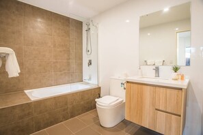 A modern bathroom with a bathtub, shower, toilet, and vanity.