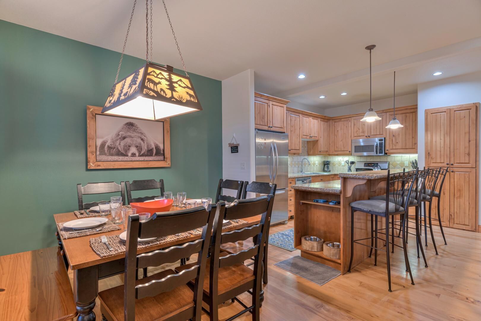 A modern kitchen with wooden cabinets, stainless steel appliances, and a dining area with a wooden table and chairs.