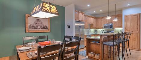 A modern kitchen with wooden cabinets, stainless steel appliances, and a dining area with a wooden table and chairs.