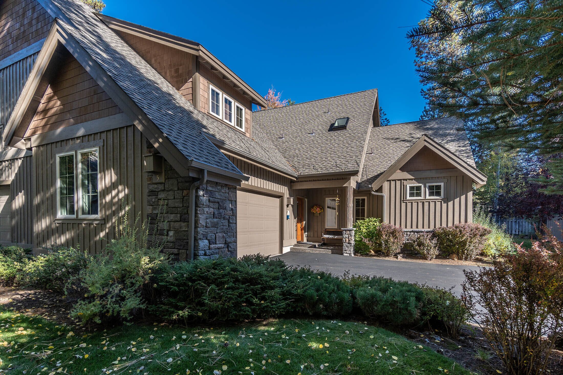 A two-story house with a stone facade, a sloped roof, and a front porch.