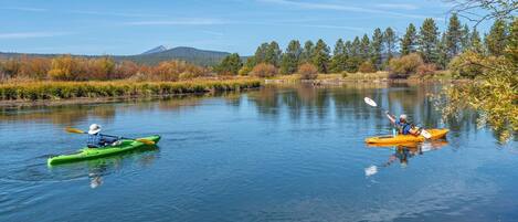 Two kayaks on a calm river with a forested landscape in the background.