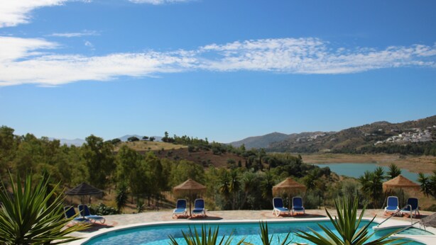 A pool area with lounge chairs and umbrellas, surrounded by greenery and hills in the background. - Cozy Rural Tourism Accommodation in Huetor Spain (Vinuela)