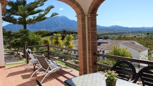 A balcony with a table and chairs, overlooking a mountainous landscape. - Cozy Rural Tourism Accommodation in Huetor Spain (Vinuela)
