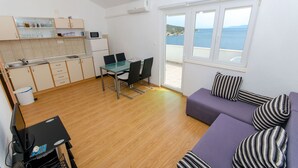 A compact living space with a kitchenette, dining area, and a sofa with striped cushions. - Apartments Ana (Vinisce)