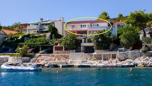 A coastal hotel with a stone facade, a pool area, and a view of the sea. - Apartments Ana (Vinisce)