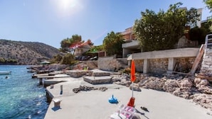 A coastal area with a clear blue sea, a concrete walkway, and a few boats. - Apartments Ana (Vinisce)