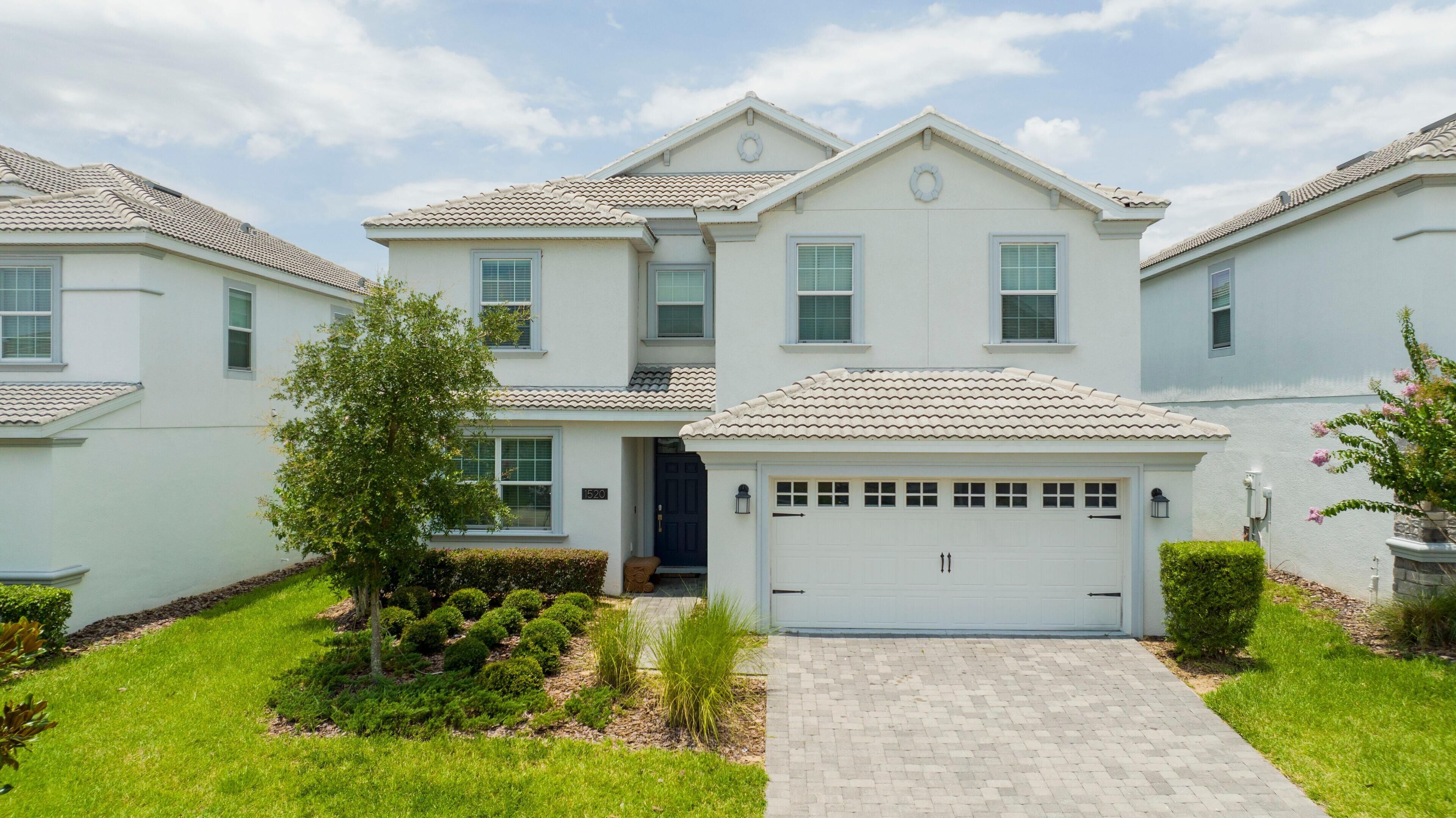 A two-story residential building with a tiled roof, a front garage, and a well-maintained lawn.