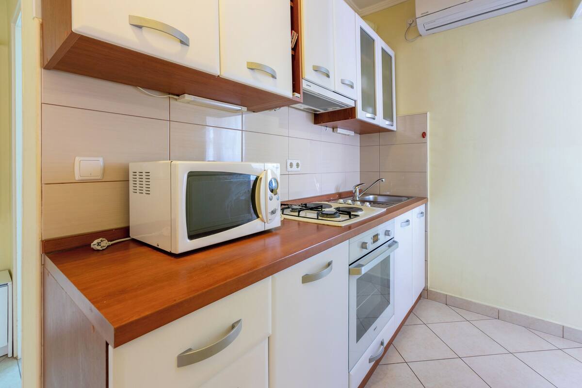 A kitchen with white cabinets, a microwave, a gas stove, and a sink.