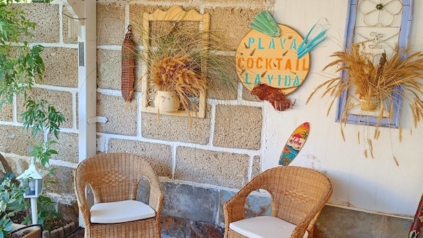 A cozy outdoor seating area with wicker chairs and a stone wall backdrop.