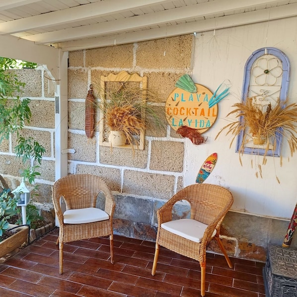 A rustic outdoor seating area with wicker chairs and a stone wall backdrop.