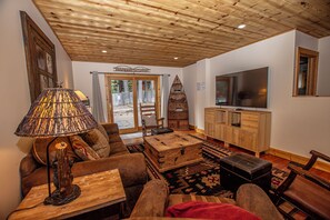 A living room with a sofa, a wooden coffee table, a lamp, a television, and a cabinet.