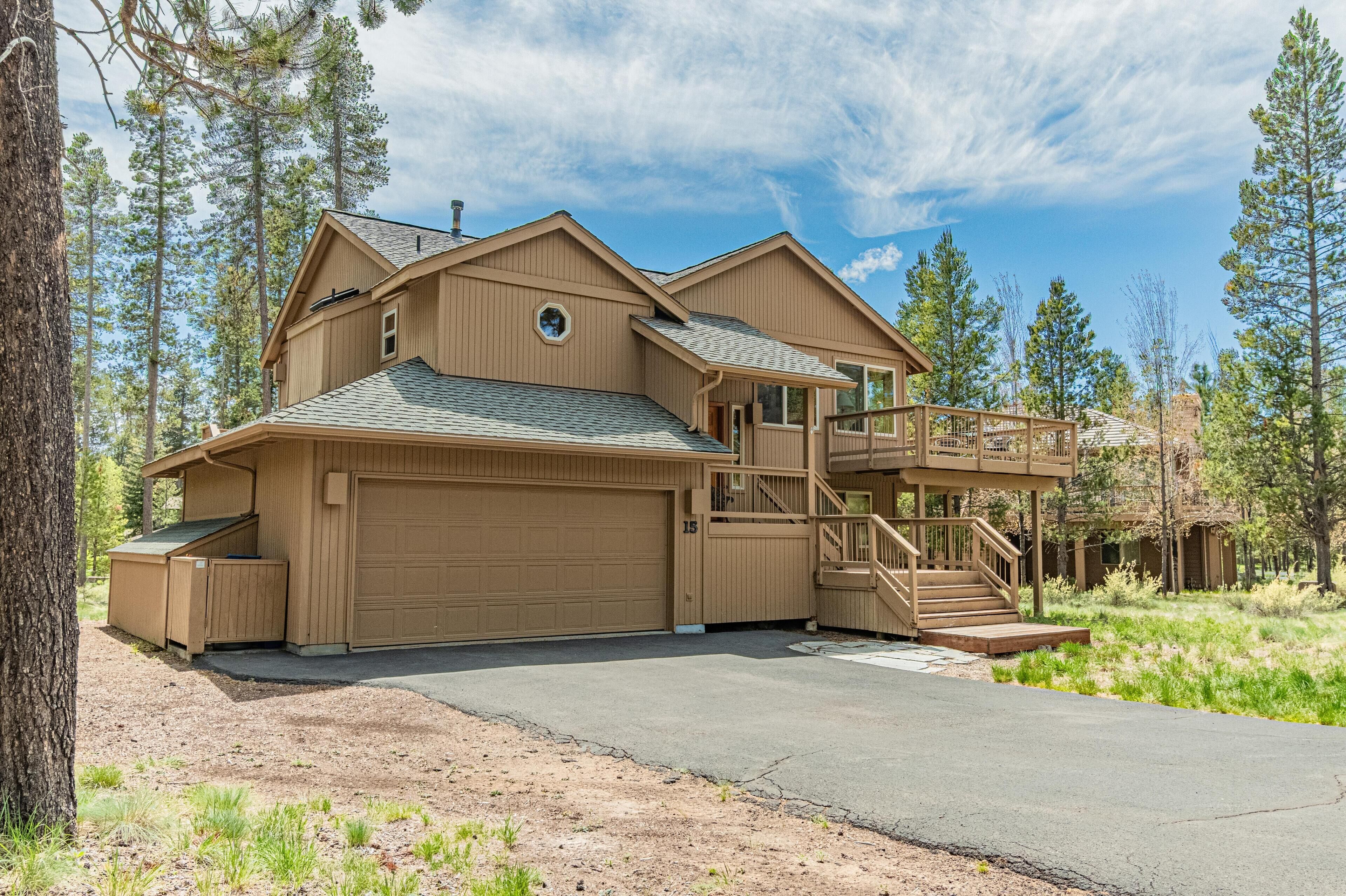 A two-story house with a garage, a covered porch, and a staircase leading to a deck.