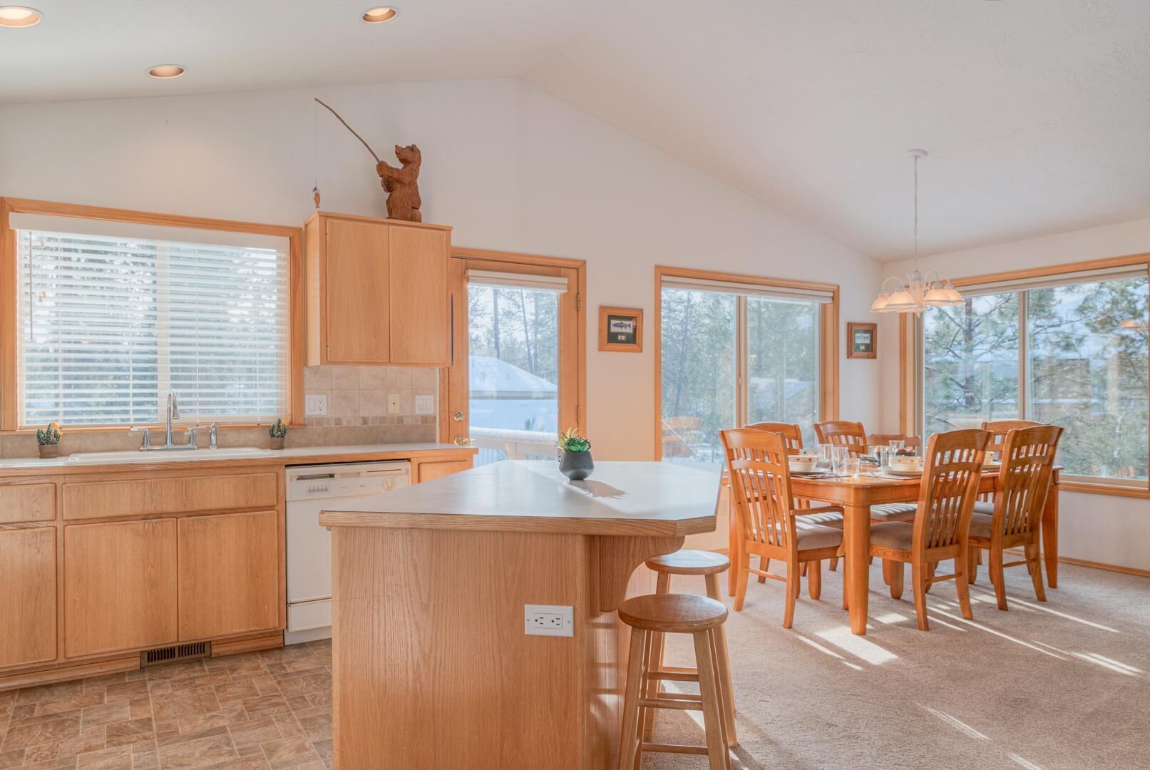 A modern kitchen with wooden cabinets, a central island, and a dining area with wooden chairs and a table.