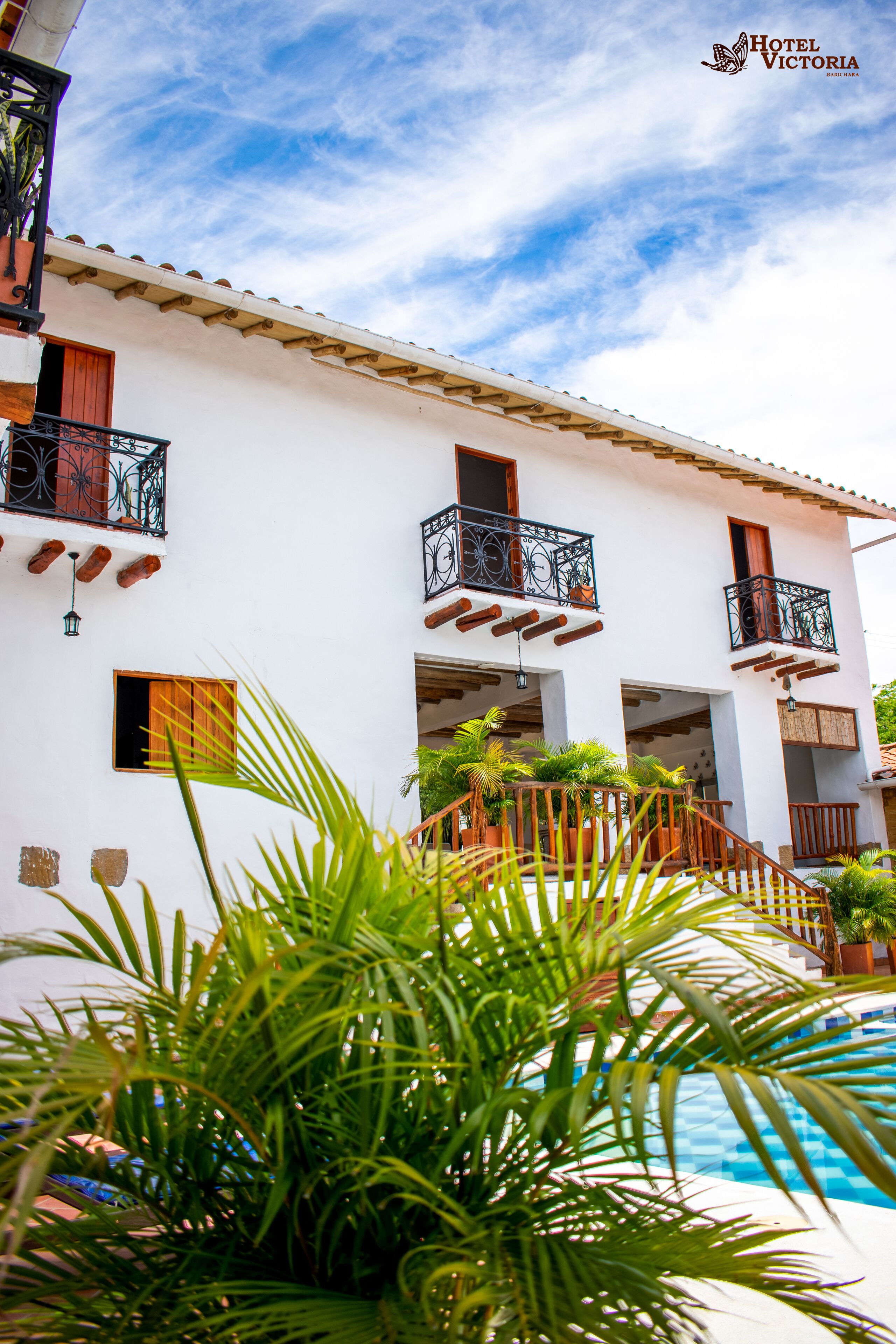 Un edificio blanco con balcones, piscina y plantas en macetas.