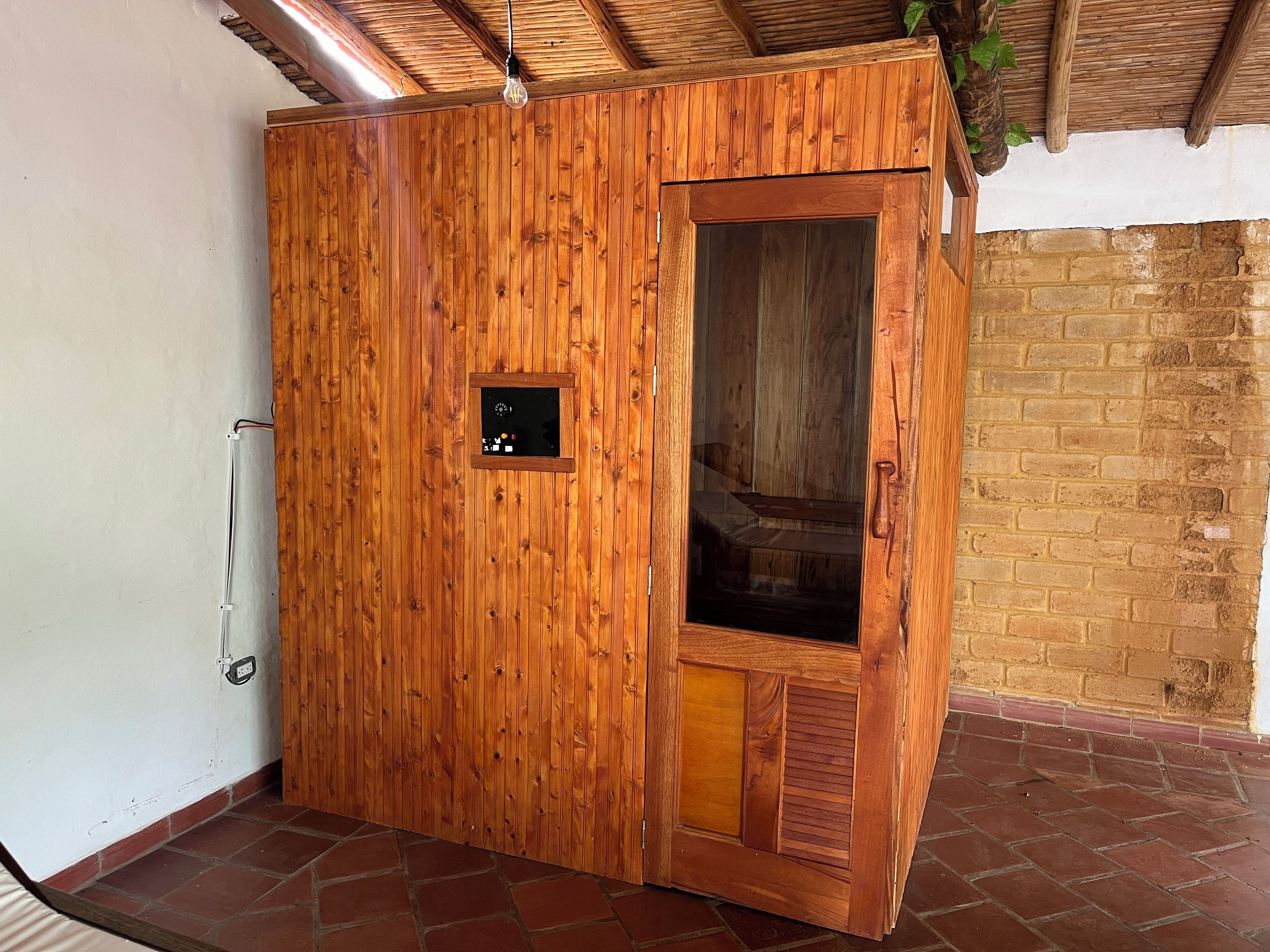A wooden wardrobe with a glass door, a small control panel, and a brick wall in the background.