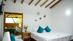 Ein Schlafzimmer mit Bett, einer Couch, einer Hängematte, einem kleinen Tisch und einer Zimmerpflanze.