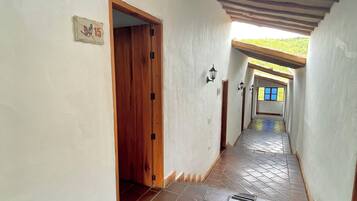Un pasillo con piso de baldosas, una puerta de madera y un letrero con número.