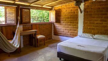 Um quarto com uma cama, uma escrivaninha e uma rede.