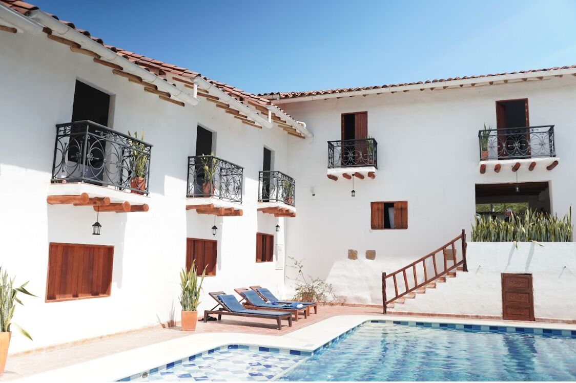 A white building with balconies, a swimming pool, and a staircase.