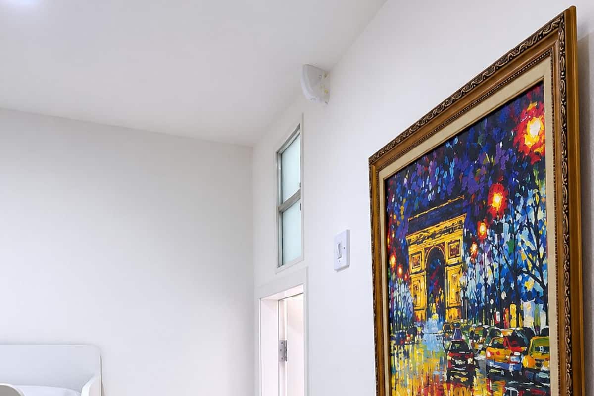 A room with a bunk bed, a door, and a painting of the Eiffel Tower.