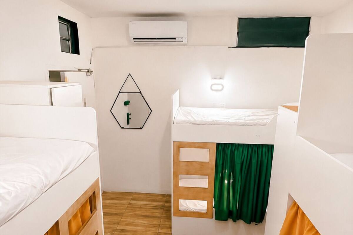 A room with two bunk beds, a small window, an air conditioning unit, and a wall-mounted light fixture.