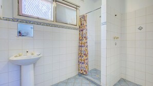 A bathroom with a white sink, a shower with a patterned curtain, and a window with a lattice design. - Ruby is the precious jewel in the heart of Exmouth. (Exmouth)