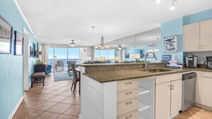 A spacious kitchen with a large island, a dining area with a view, and a living room with a balcony. - On the Gulf-Beach Bum Getaway-Free Beach Chair Setup! (Miramar Beach)