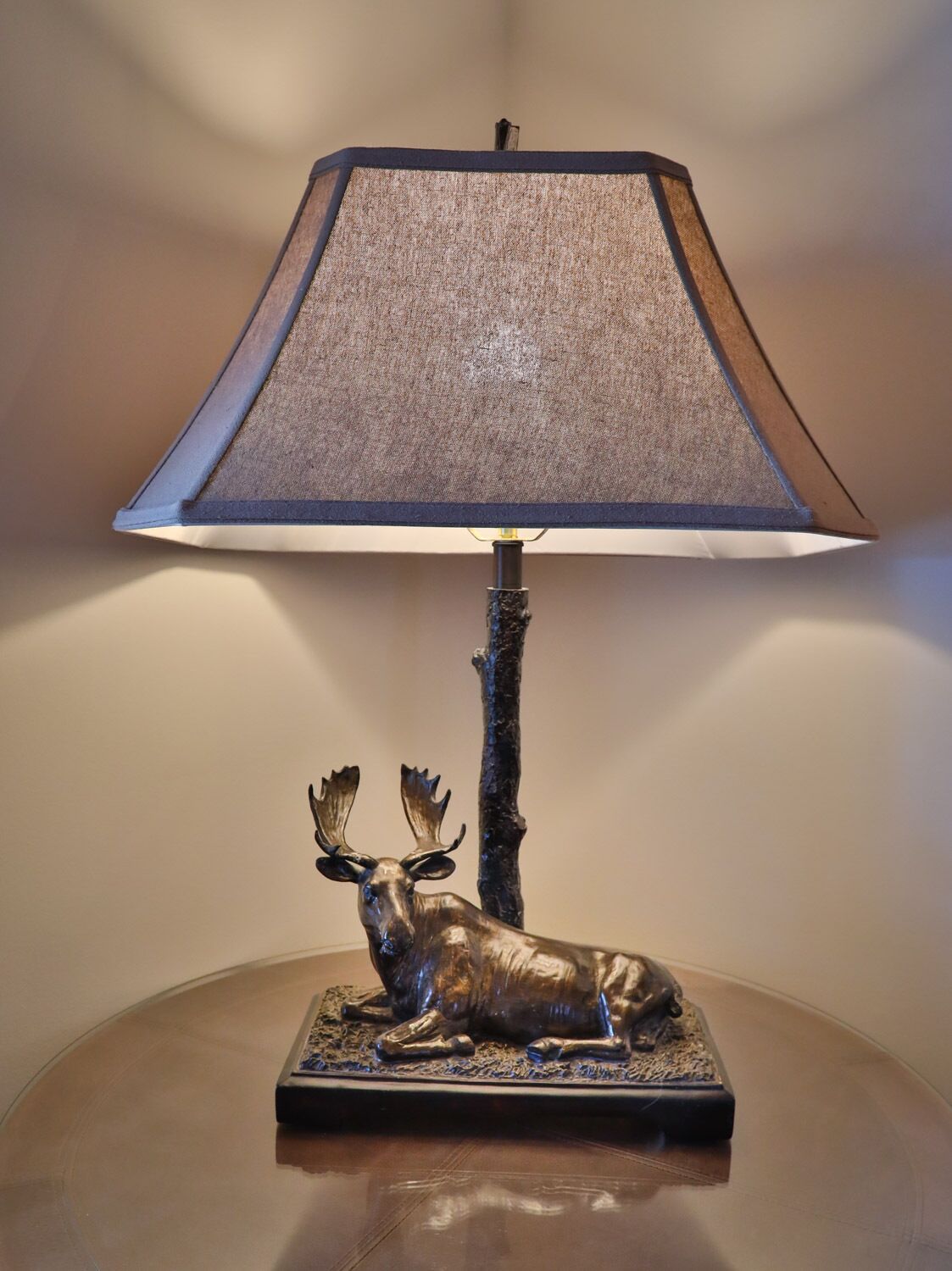 A lamp with a textured shade and a deer figurine base.