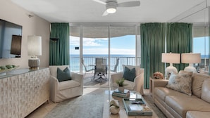 Un vaste salon avec balcon donnant sur la mer, aménagé avec un canapé, des fauteuils et une table basse.