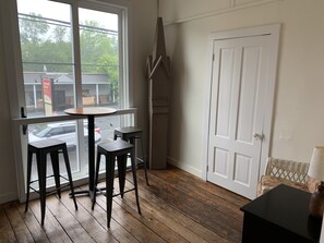 A room with a large window, a door, and two stools.