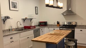 A modern kitchen with white cabinets, a wooden island, bar stools, and a stainless steel range hood. - Newly renovated in-town Bar Harbor, five bdrm apartment. Walk to shore & shops. (Bar Harbor)