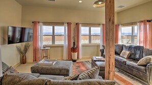 A living room with a large window, a flat-screen TV, a sofa, and a coffee table. - Unique Cortez Family Getaway w/ Mountain Views! (Cortez)