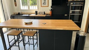 A modern kitchen with a wooden island, black cabinetry, and stainless steel appliances. - New house with swimming pool and large outdoor terrace. (VENCE)