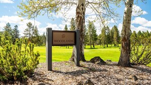 A sign labeled "WOODLANDS" in a park setting with trees and a grassy area. - 2 Living Rooms, A/C, King beds, Near River, Hot Tub, Air Hockey, SHARC Passes (Sunriver)