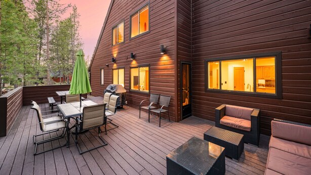 A wooden cabin with a deck, outdoor seating, and multiple windows. - 2 Living Rooms, A/C, King beds, Near River, Hot Tub, Air Hockey, SHARC Passes (Sunriver)