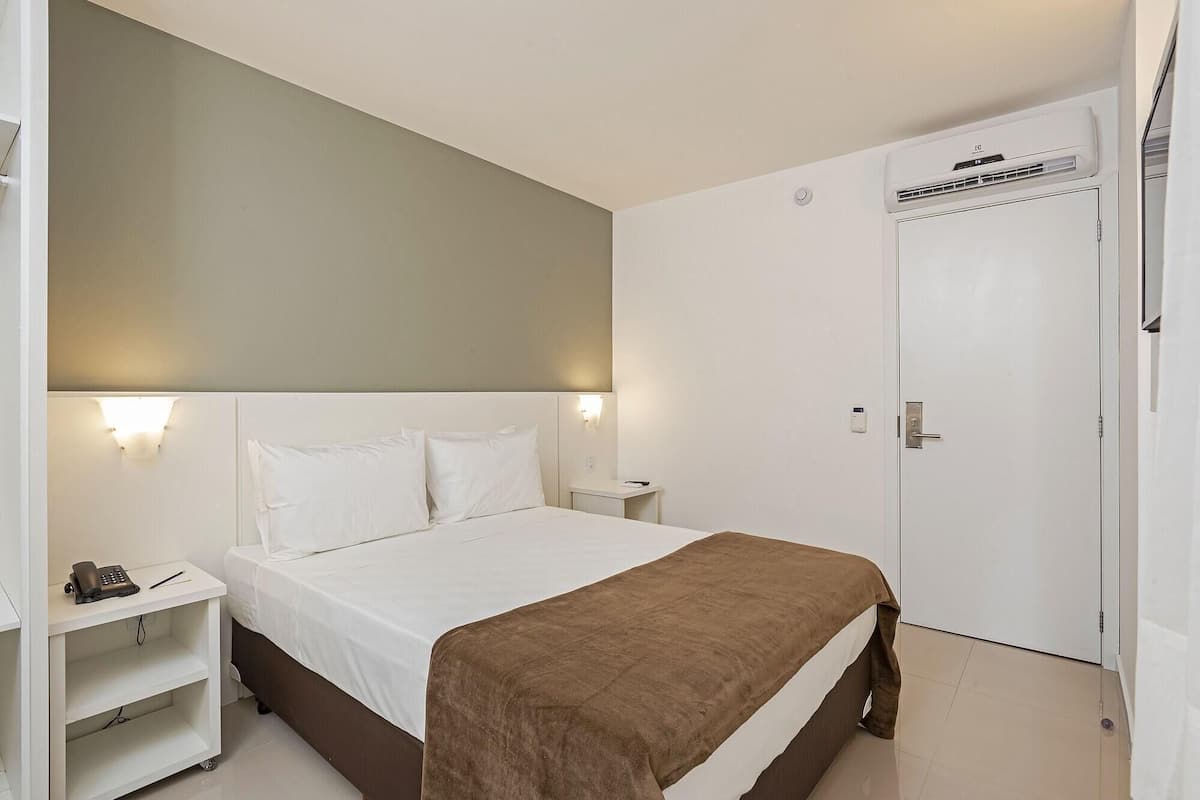 Une chambre d’hôtel avec un lit, une table de chevet et une armoire.