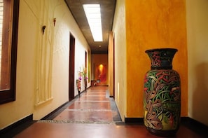 A hotel corridor with a large decorative vase, wooden doors, and a tiled floor. - Casa Mar Verde (Montenegro)