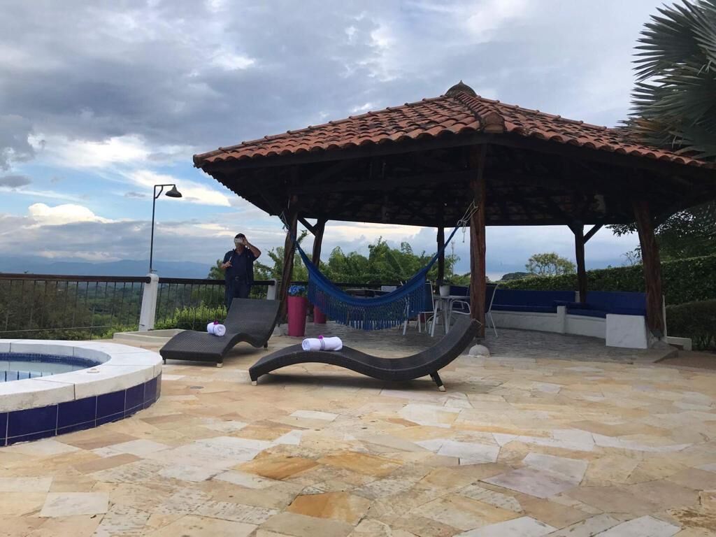 A rooftop pool area with a tiled floor, a hammock, lounge chairs, and a gazebo.