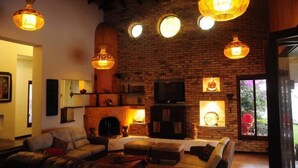A cozy living room with a brick fireplace, a television, and hanging pendant lights. - Casa Mar Verde (Montenegro)