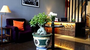 A reception desk with a sign reading "HIGHEST VIBRANT HOTEL," a potted plant, a purple sofa with an orange pillow, and a lamp. - OASIS-NEAR BEACH-STUDIO ROOM (Da Nang)
