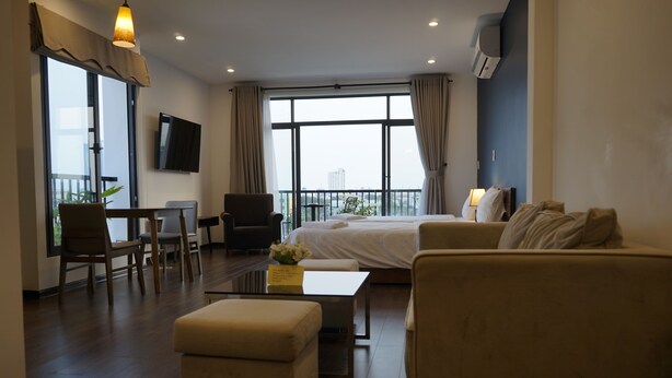 A hotel room with a bed, two sofas, a coffee table, a TV, and a balcony with a view. - OASIS-NEAR BEACH-STUDIO ROOM (Da Nang)